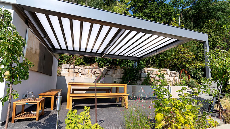Lamellendach als Sonderform in eine Natursteinterrasse integriert.